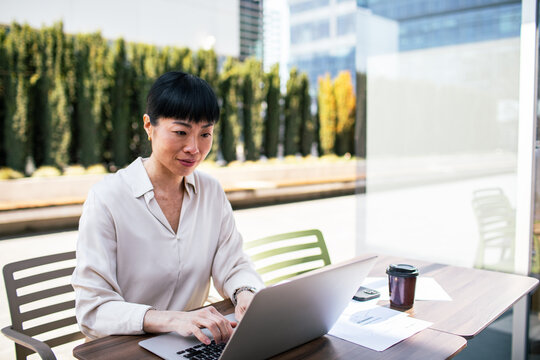 Businesswoman working on laptop at outdoor cafe