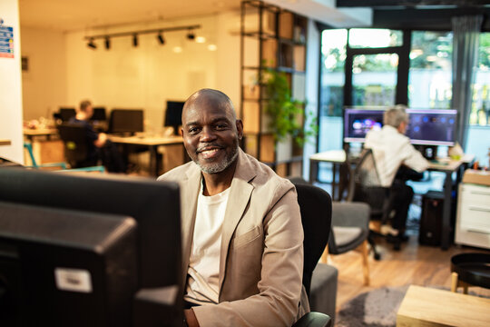 Smiling businessman at computer in modern open office