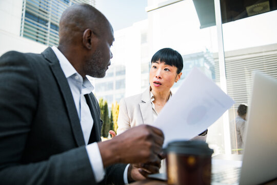 Two business colleagues discussing documents on outdoor office terrace
