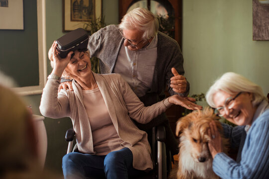 Senior friends enjoying virtual reality at home with dog