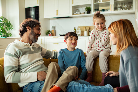 Parents and children talking on sofa in home kitchen