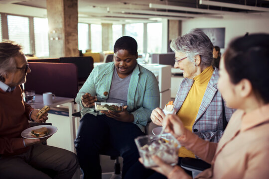 Multigenerational coworkers sharing lunch in modern office