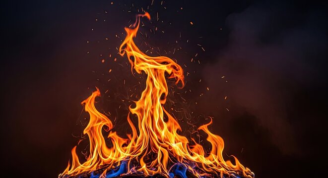 A fiery bonfire with orange and yellow flames against a dark background, with sparks flying and a black smoke cloud.