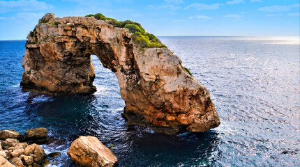 Natural rock arch in the sea with lush green vegetation © erna