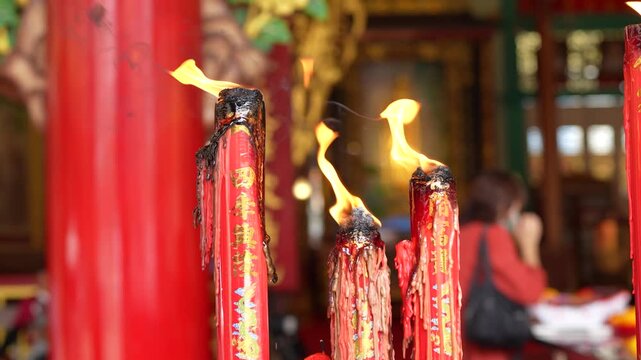 ed Chinese candles with gold calligraphy at a traditional shrine during daytime.