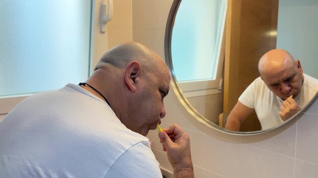 Hombre cepill&aacute;ndose los dientes frente al espejo