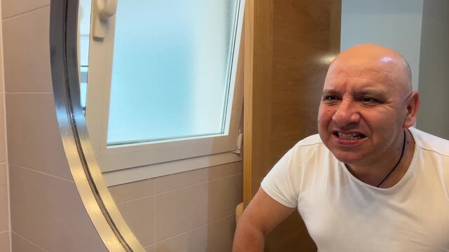Hombre observando sus dientes limpios frente al espejo del ba&ntilde;o