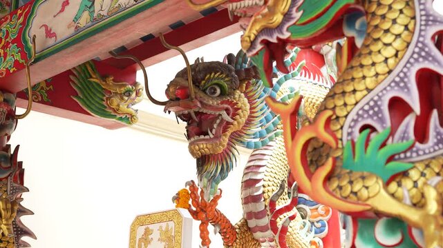 Detailed Chinese dragon sculpture decorated on a temple pillar in daylight.