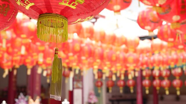 Traditional red Chinese lanterns hanging in a row at a shrine entrance.