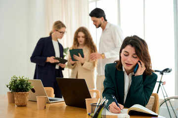 Fototapeta premium Businesswoman multitasking with phone and writing in office