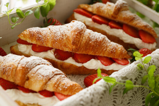 Croissants with strawberries and whipped cream, close-up. A delicious dessert or breakfast.