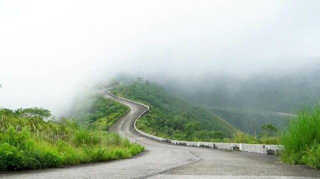 Handheld point of view walking up a winding concrete road covered in thick white fog toward the Mount Kelud crater peak in Kediri, East Java, Indonesia