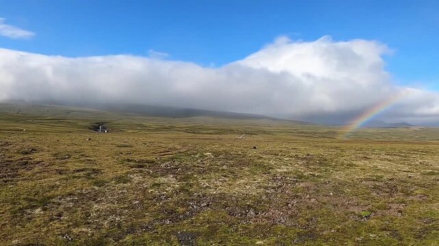 Scenic Icelandic highlands with a rainbow and rolling clouds