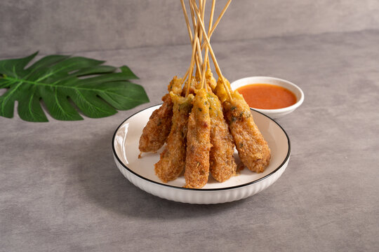 Sempol ayam skewers served on a plate with spicy chili sauce on dark background. Sempol made from chicken, spices and eggs. Popular Indonesian street food snack