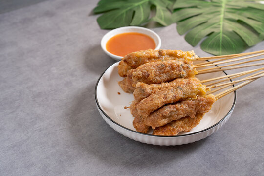 Sempol ayam skewers served on a plate with spicy chili sauce on dark background. Sempol made from chicken, spices and eggs. Popular Indonesian street food snack