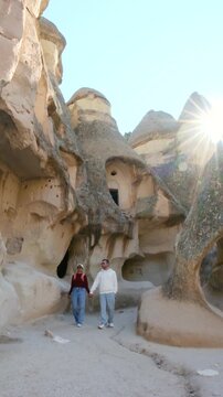 Visitors wander through Cappadocia Turkey stunning landscape, marveling at unique rock formations and ancient caves. Sunlight filters through the stunning scenery, creating a magical atmosphere.