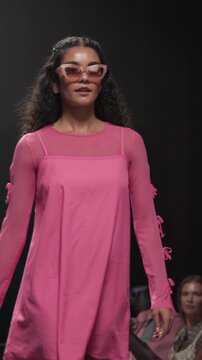 Stage, fashion model and woman on walk, performance and showcase of clothes, confident and creative. Advertising, outfit and person with stylish dress, bold and colorful with eyewear on runway