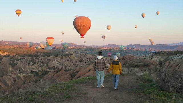 Colorful hot air balloons rise gracefully above Cappadocia, Turkey as visitors enjoy breathtaking views. The sky turns golden, creating an enchanting atmosphere perfect for travel lovers.