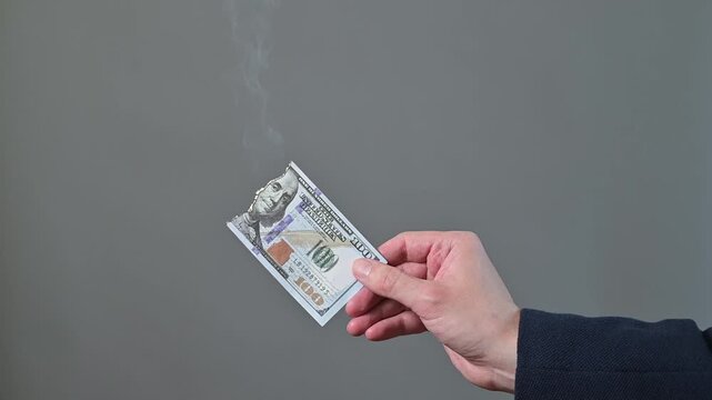 A hand holds a paper item as smoke rises from it in four frames.