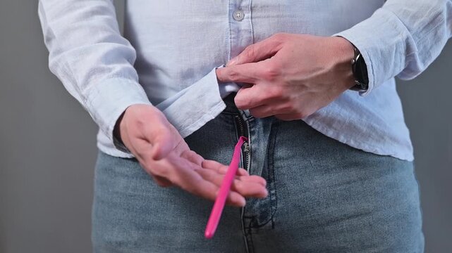 Impotence, a male health problem concept. Close-up of an unrecognizable man touching a deflated balloon hanging from his pants.