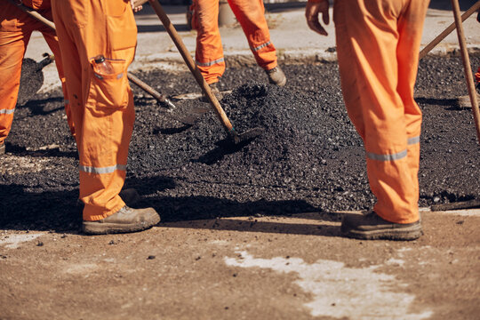 Construction worker working on a new asphalt layer on a public street.