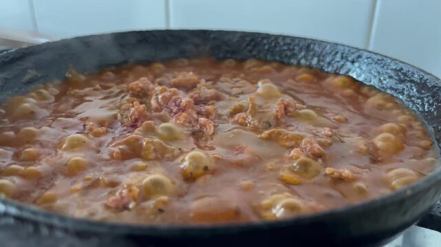 Homemade meat sauce boiling in an old frying pan, steam and bubbles