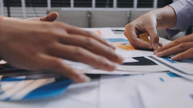 Asian women working together as web designers in an office, pointing at whiteboard with uxui mobile app wireframe