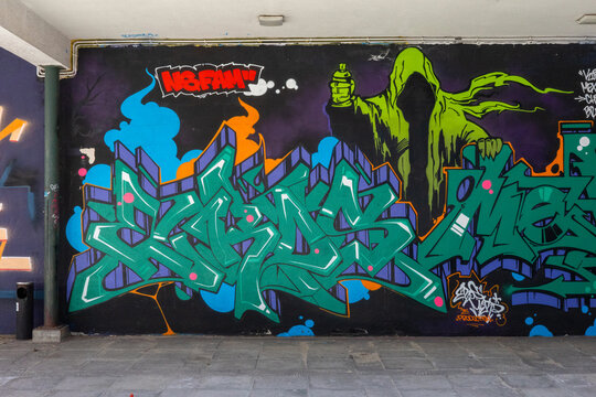 WARSAW, MASOVIAN VOIVODESHIP, POLAND - APRIL 23, 2026: A vibrant and detailed piece of street art featuring stylized lettering and a hooded figure.