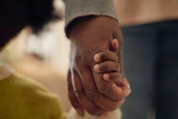 Close up of Black parent holding child hand, walking together and expressing poverty, care,...