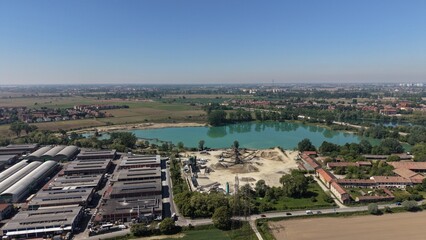 Fototapeta premium Aerial Vista: A picturesque aerial shot showcases a serene lake embraced by the beauty of nature, with industrial infrastructures and town. The image encapsulates the intersection of industry.
