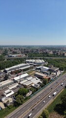 Obraz premium Aerial View of a bustling industrial landscape: A bird's-eye view unveils a vibrant scene of an industrial complex, crisscrossed by a busy highway, under a clear, endless blue sky.