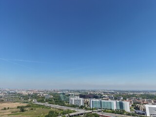 Obraz premium Cityscape Under a Vast Blue Sky: An expansive view of a city sprawling beneath a clear, endless blue sky, offering a sense of openness and boundless opportunity.