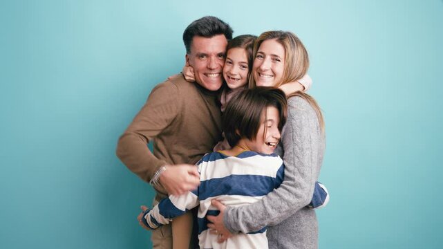 Joyful parents with their son and daughter smiling and hugging each other. Beautiful family portrait expressing love and happiness
