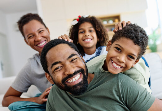 Portrait of a happy black family mother father and kids at home on couch