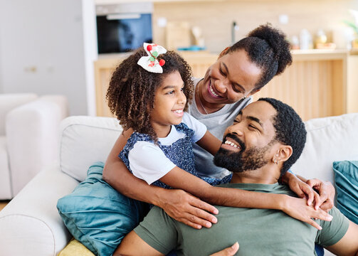 Portrait of a happy black family mother father and daughter at home on couch