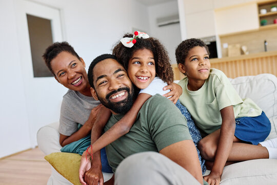 Portrait of a happy black family mother father and kids at home on couch
