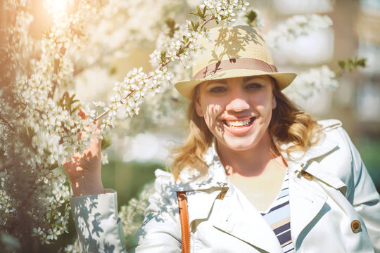 Woman in hat near cherry blossom. Floral garden, romantic mood and bright sparkling happiness.