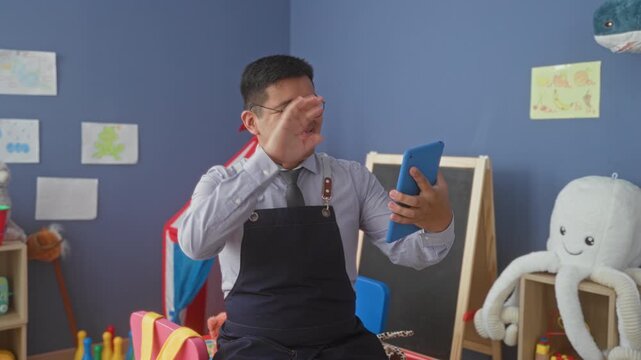 Man teacher holding tablet, smiling and pointing with hand in school building; joyful teaching connection.