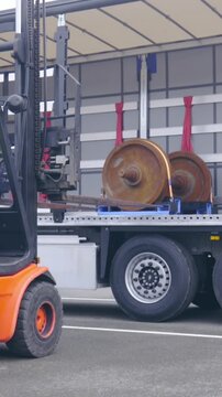 Forklift unloading wheelbase cargo on pallet from truck trailer wide shot