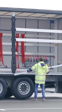 Worker remove truck trailer protective fence in slow motion