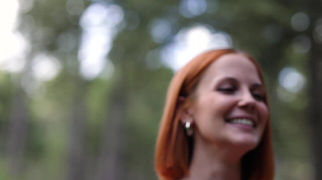 Close up of a happy young woman with red hair genuinely laughing. Cheerful female enjoying a beautiful day in a park with a natural smile