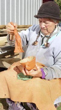 Cauquenes, Chile - March 26, 2026: An artisan proceeds to apply the "colo", a paste that gives the characteristic reddish-brown color to clay pieces such as plates, cups, jugs, among others.