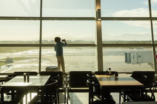 young boy taking photos from airport window,