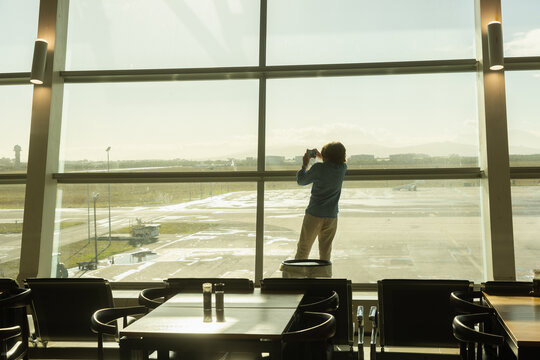 young boy taking photos from airport window,