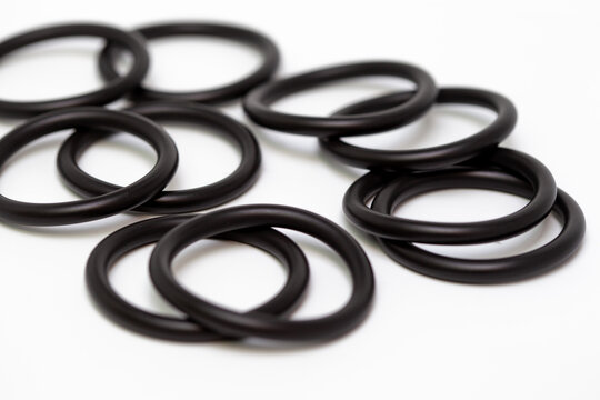 Top view macro shot of multiple black rubber O-ring seals arranged in a geometric pattern on a clean white background, showcasing industrial sealing components