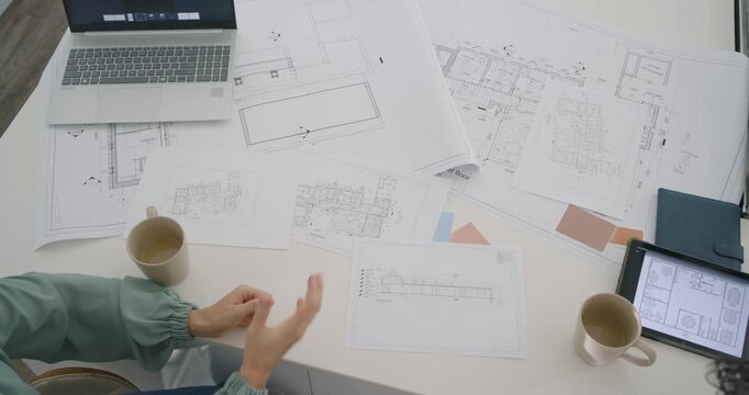 Two women reviewing plans at office table, woman tracing marks in sage top, copy space