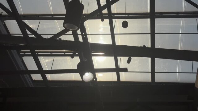 Sunlight Rays Through Industrial Glass Roof in Modern Interior 4K. Cinematic sunlight rays shining through large glass roof windows in an industrial modern interior. 