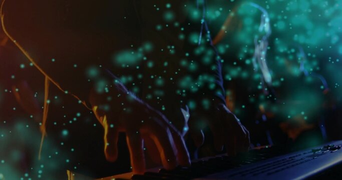 Typing hands wearing long-sleeve pressing keys at workstation, keyboard and teal particle overlay