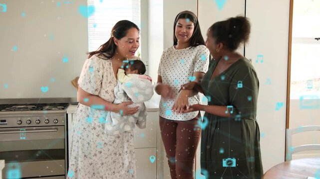 Women stepping greeting and admiring mom holding wrapped baby in kitchen, blue AR hearts for health