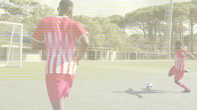 Foreground player shifting forward while teammate running up and striking ball in soccer training